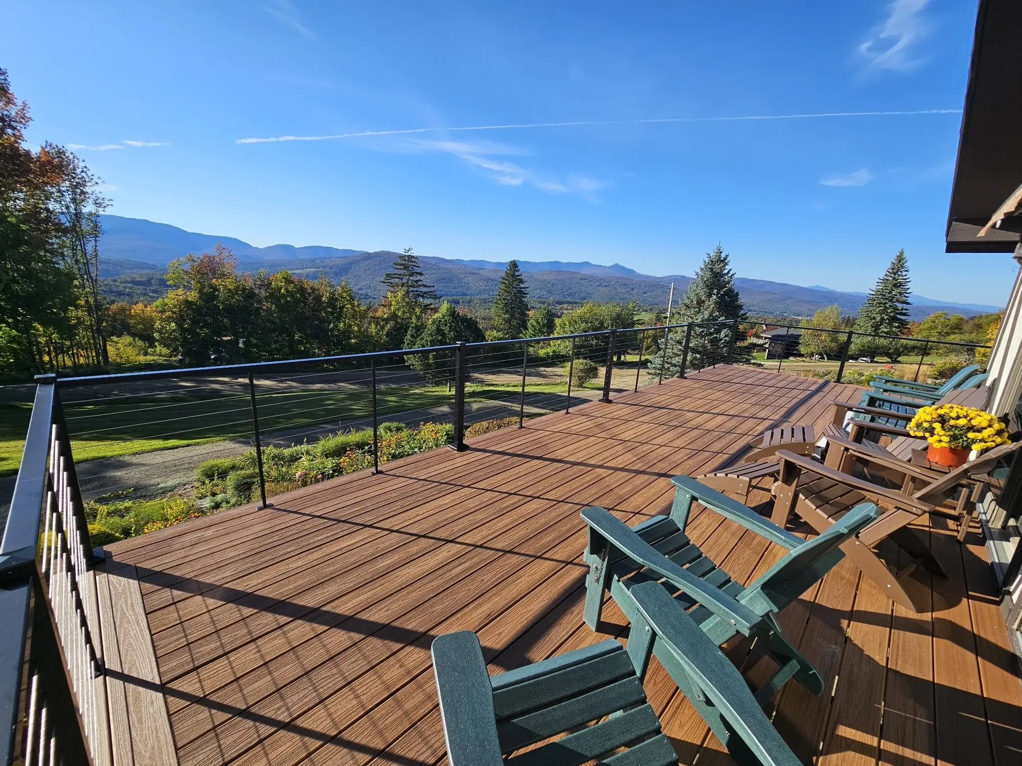 Finished Trex deck with black cable railing and Adirondack chairs, looking out over the mountains in Waitsfield, Vermont