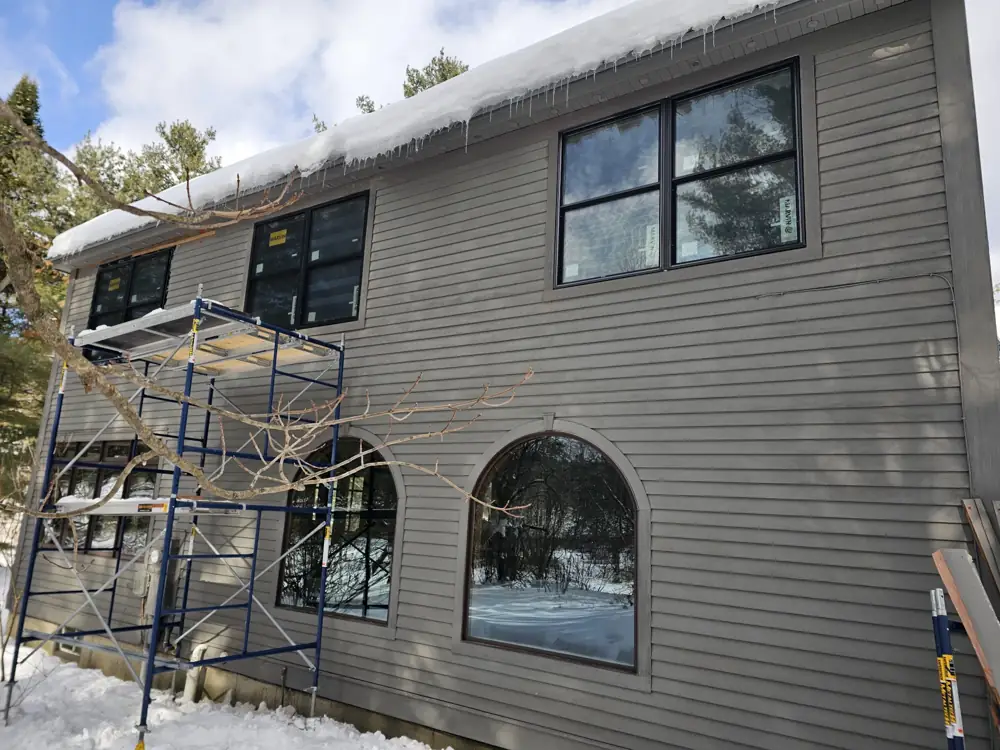 Row of new black Marvin windows on the second floor, scaffolding beside