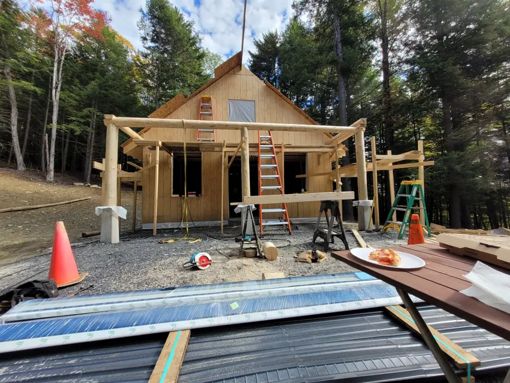 Round log porch posts and beam being set on concrete piers