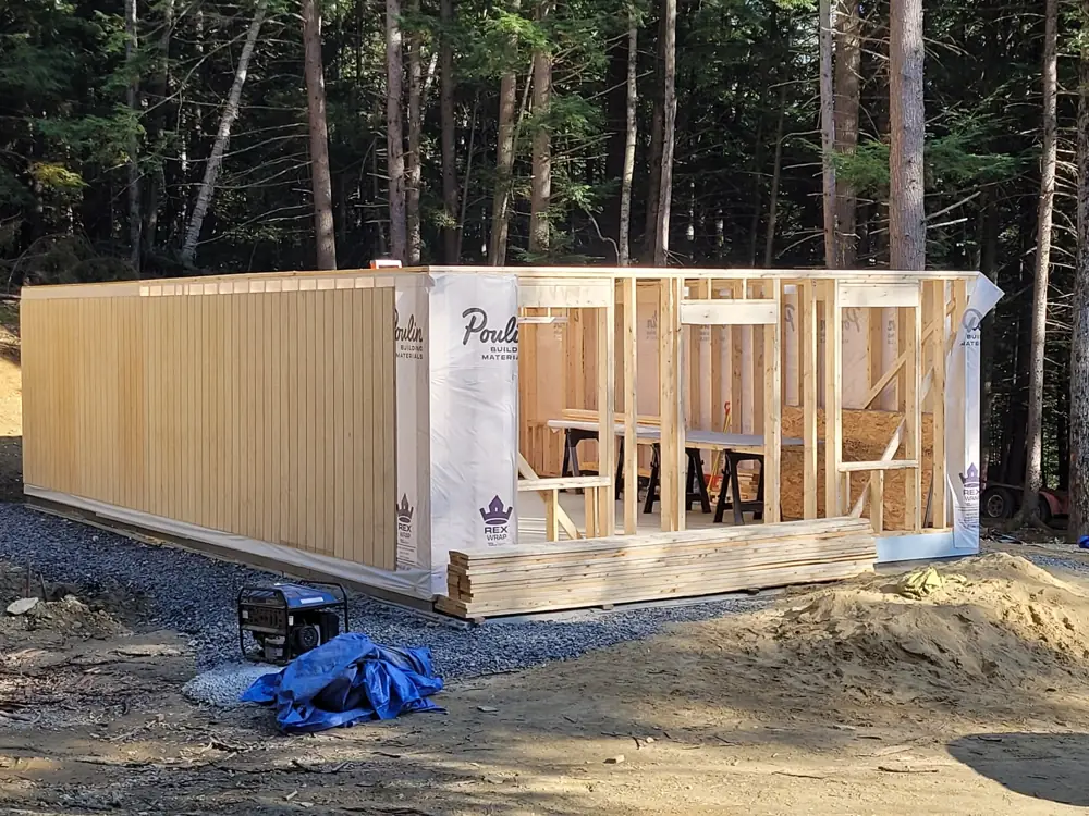 New building with walls framed, sheathed and house-wrapped in the woods
