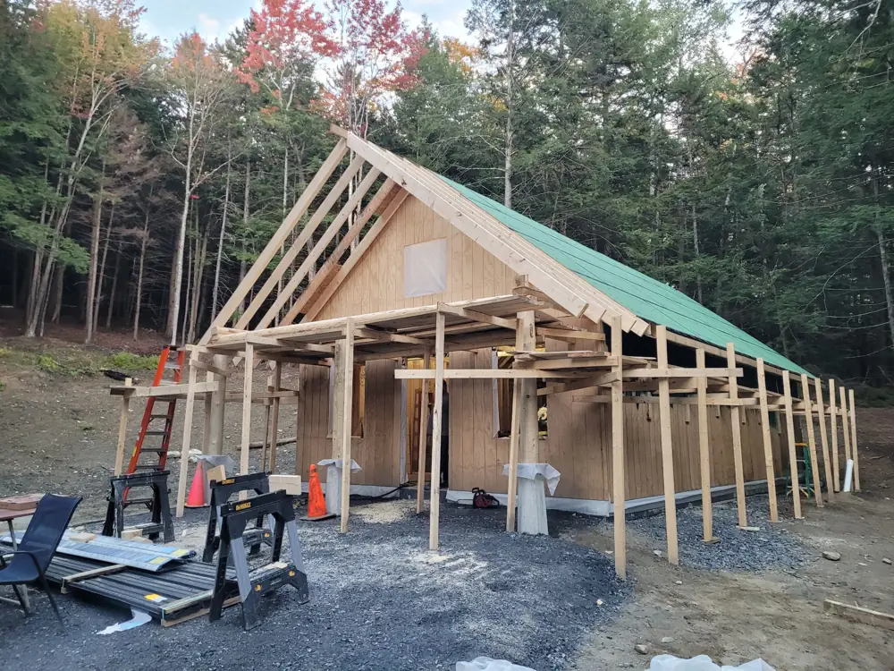 Full roof sheathed in green ZIP panels, rafter tails at the gable