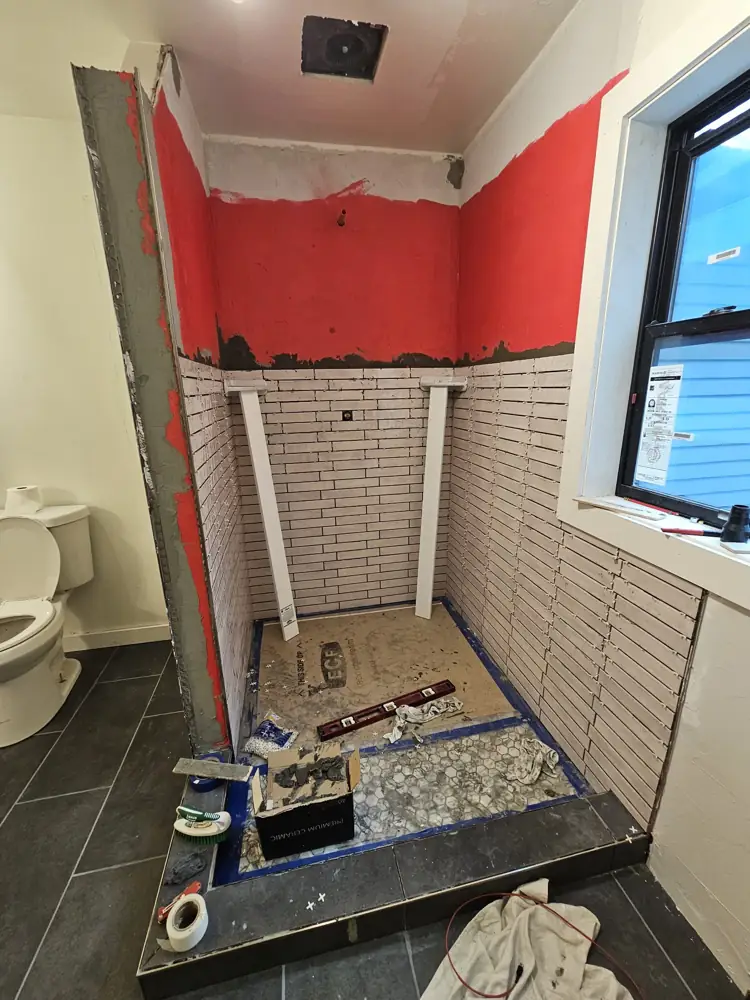 Shower walls waterproofed in red membrane with tile going up